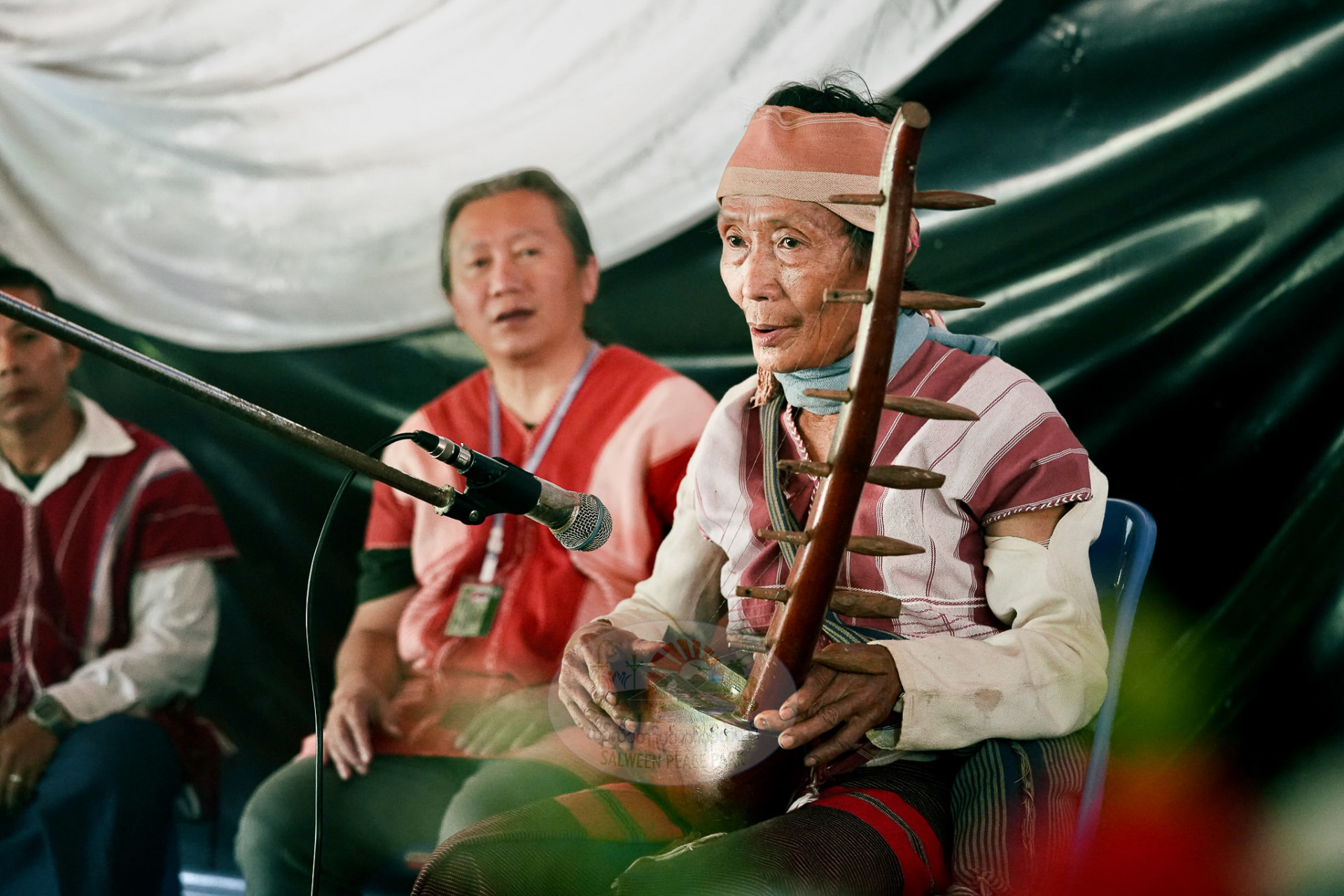 A Karen elder playing a traditional stringed instrument at a community gathering